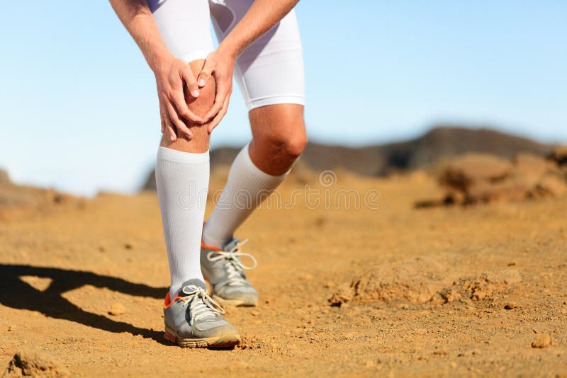 Running injury - Male runner with knee pain. Trail runner injured jogging in nature clutching his knee in pain. Man fitness athlete. Running injury - Male runner with knee pain. Trail runner injured jogging in nature clutching his knee in pain. Man fitness athlete.