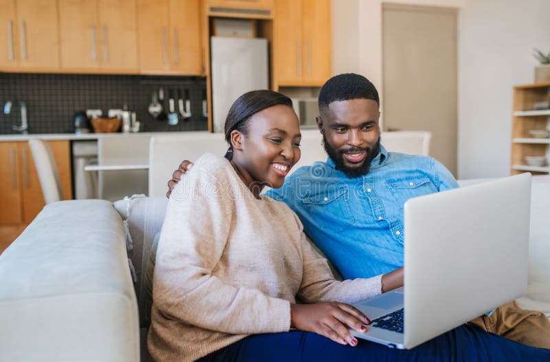 Laughing African American couple using a laptop together at home