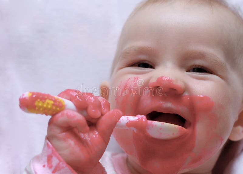 Laughing baby with a spoon in the mouth