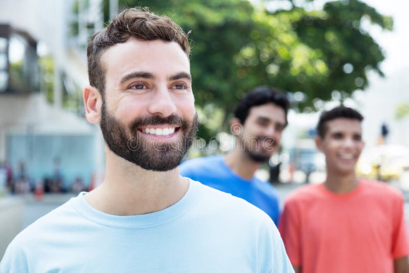 Laughing caucasian man with beard walking with two friends in the city