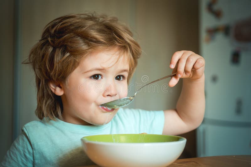 Laughing cute child baby boy sitting in highchair and eating on blurred background. Cheerful baby child eats food itself royalty free stock images Laughing cute child baby boy sitting in highchair and eating on blurred background. Cheerful baby child eats food itself royalty free stock images