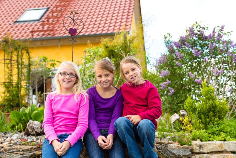 Laughing kids sit in front of the house in the garden