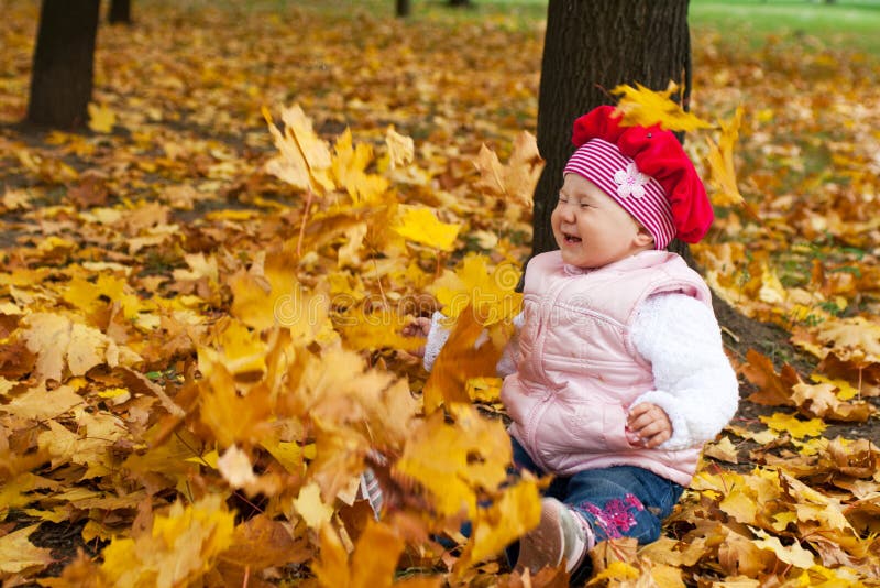 Laughing toddler and falling leaves