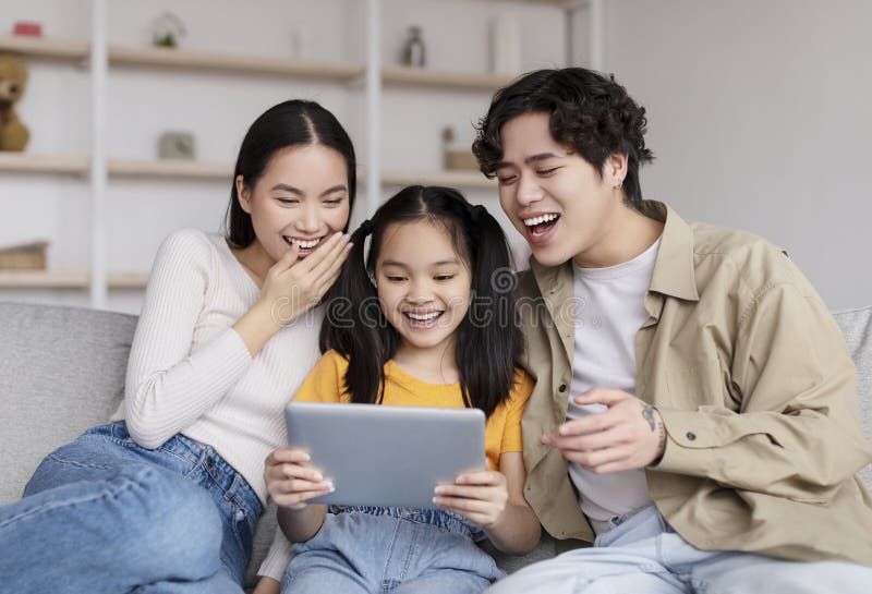 Laughing Young Asian Husband, Wife and Teen Daughter Watching Funny ...