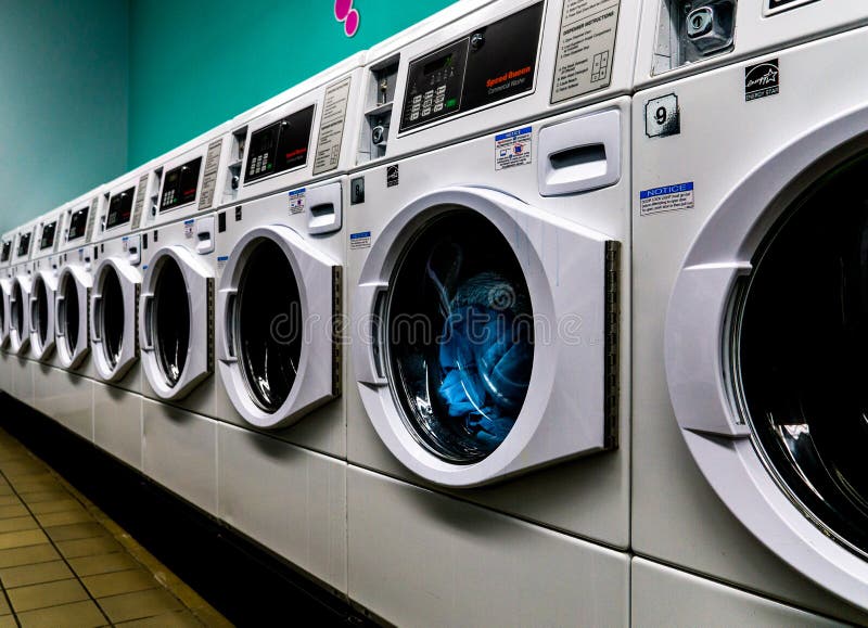 Laundromat Line of White Washing Machines with Laundry in Them and is