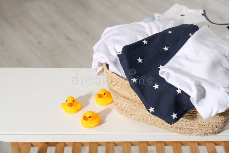 Laundry Basket with Baby Clothes and Rubber Ducks on Table in Bathroom