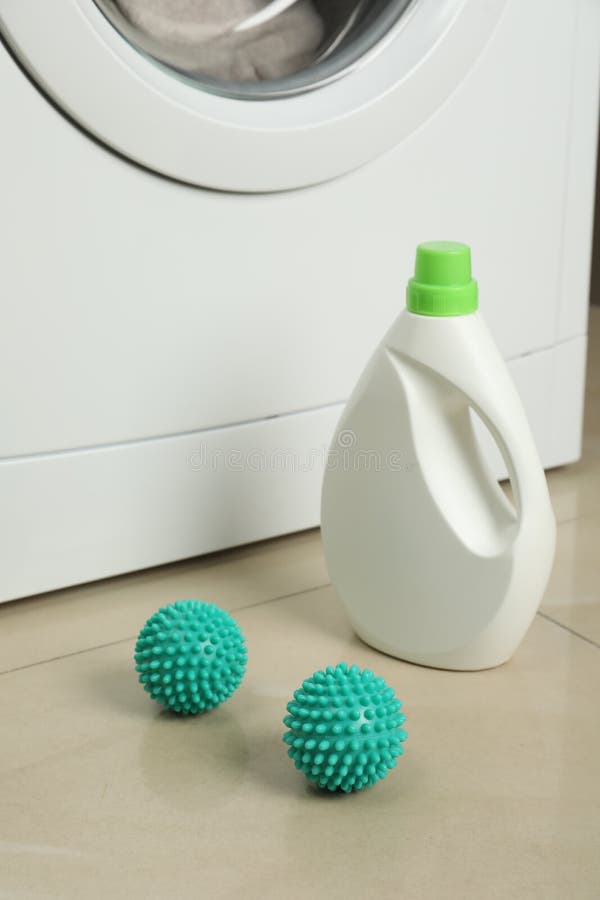 Laundry Detergent and Dryer Balls Near Washing Machine on Floor Stock