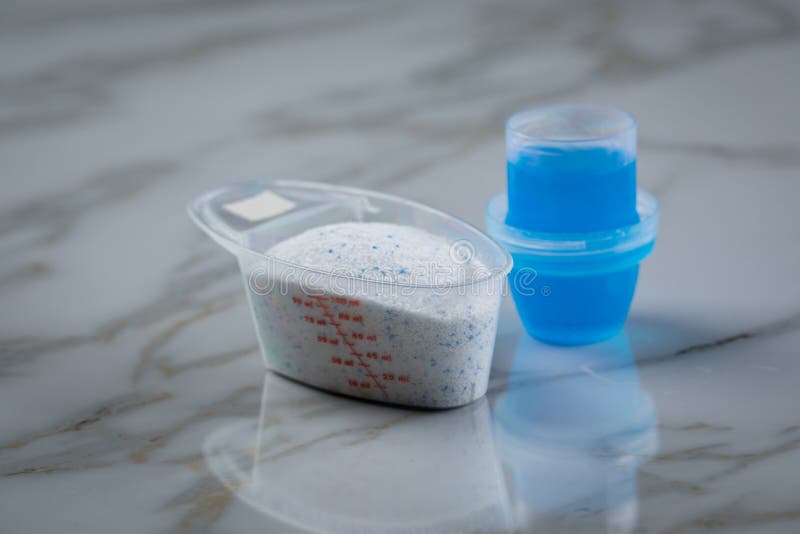 Laundry Detergent Powder and Blue Liquid Gel in Measuring Cup