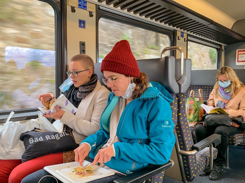 Lausanne, Switzerland - October 11, 2020: Couple on a train with a surgical mask off their face eating.