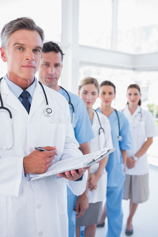 Lavagna per appunti seria della tenuta di medico e condizione davanti al suo me fotografia stock Lavagna per appunti seria della tenuta di medico e condizione davanti al suo me fotografia stock