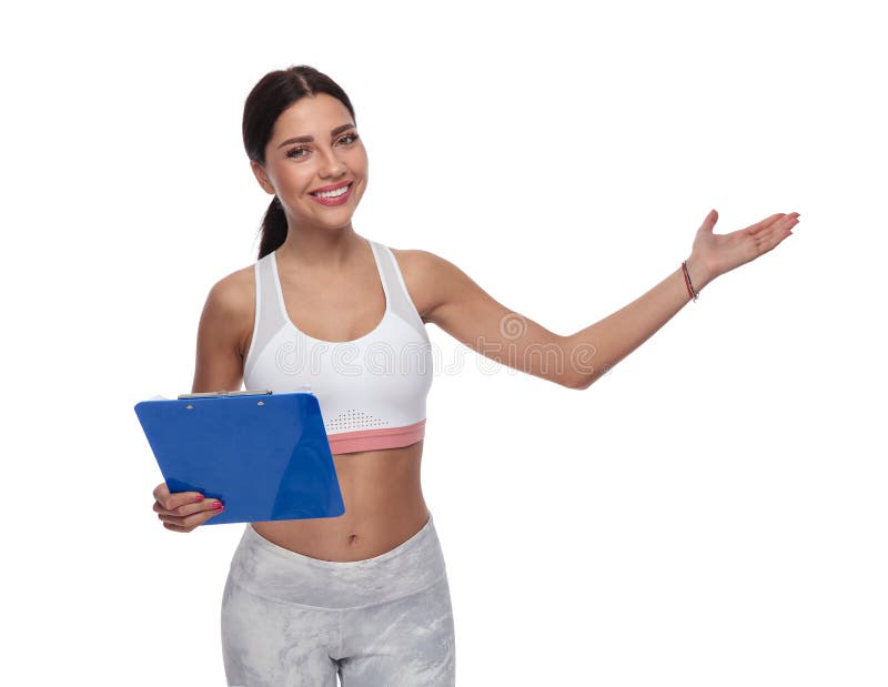 Lavagna per appunti sorridente della tenuta della donna di forma fisica e presentare al lato immagine stock Lavagna per appunti sorridente della tenuta della donna di forma fisica e presentare al lato immagine stock