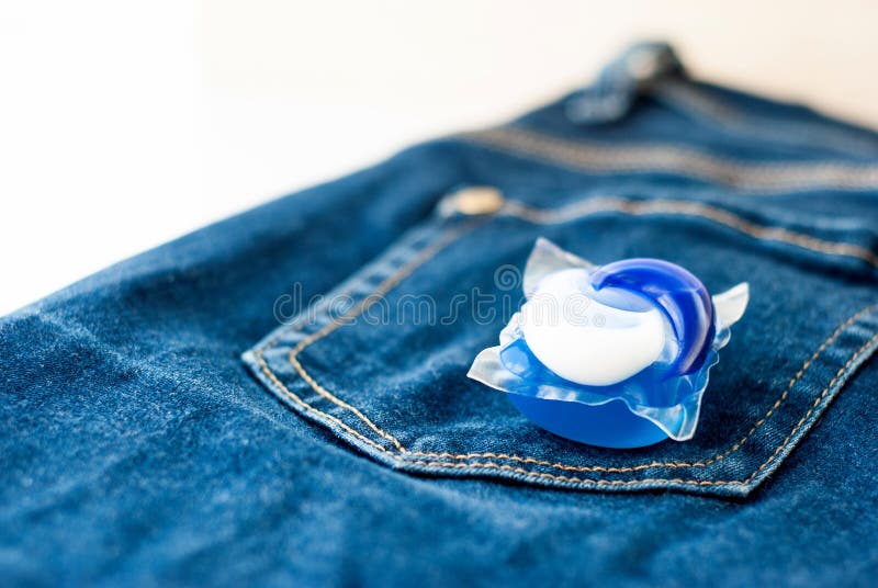 Lavanderia e baccello detergente della capsula sui jeans fotografia stock libera da diritti Lavanderia e baccello detergente della capsula sui jeans fotografia stock libera da diritti