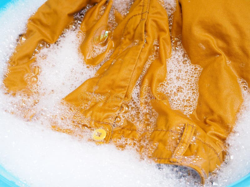 Hand wash colored clothes with yellow pants, soaked washing with laundry detergent solution in tub. Hand wash colored clothes with yellow pants, soaked washing with laundry detergent solution in tub.