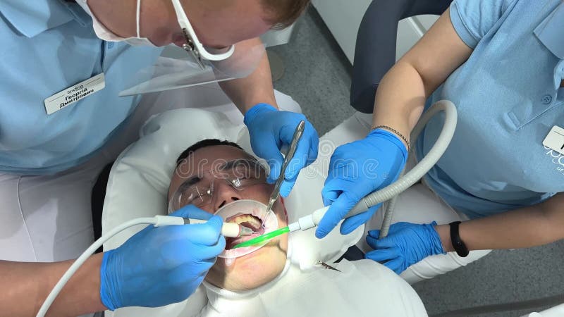Lavare i denti e lucidare il dentista ambulante che lavora su un paziente seduto sulla sedia. medico in guanti blu