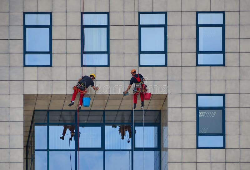 Lavavetri che lavorano alla costruzione, pulente la facciata immagine stock Lavavetri che lavorano alla costruzione, pulente la facciata immagine stock