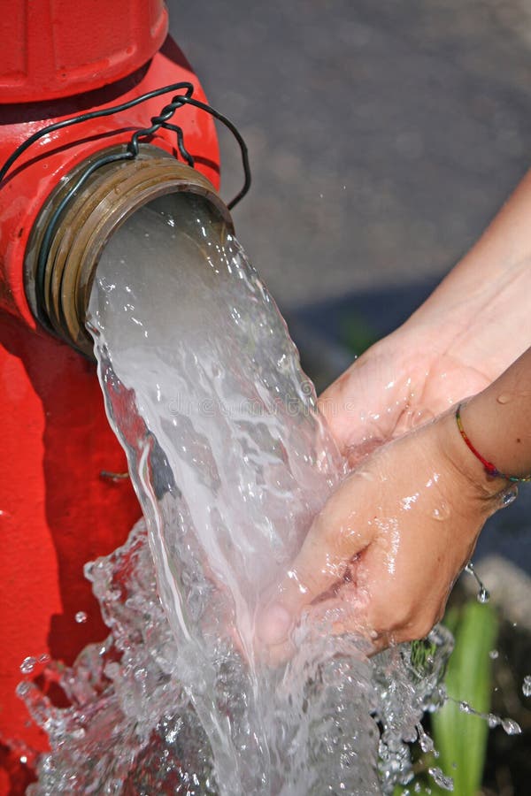 Wash hands under the powerful jet of water from a fire hydrant. Wash hands under the powerful jet of water from a fire hydrant