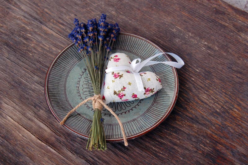 Vintage background with lavender flower and heart shaped lavender bag on wooden table