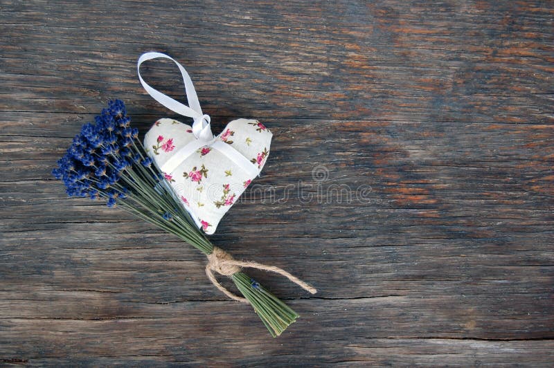 Vintage background with lavender flower and heart shaped lavender bag on wooden table