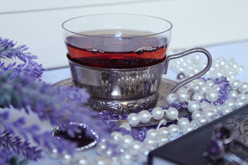 Lavender, pearls and notebook on the background of black tea in a beautiful Cup, shot close-up