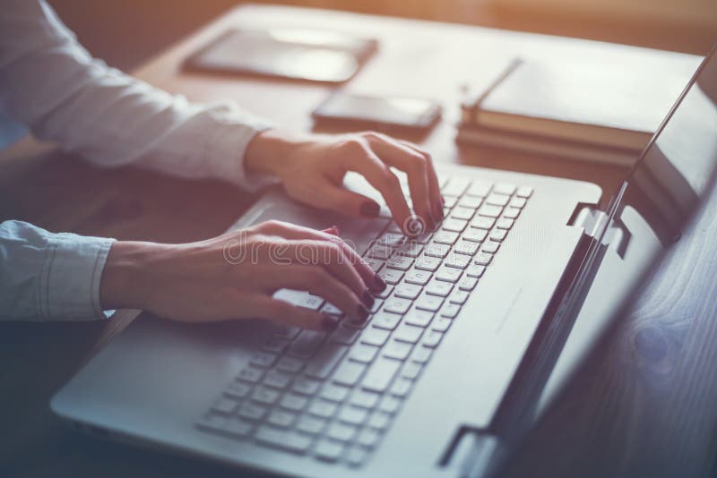 Lavorando a casa con la donna del computer portatile che scrive un blog Mani femminili sulla tastiera