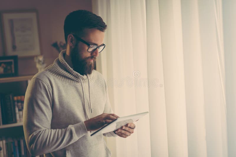 Handsome young entrepreneur working in a home office, using a tablet computer. Handsome young entrepreneur working in a home office, using a tablet computer