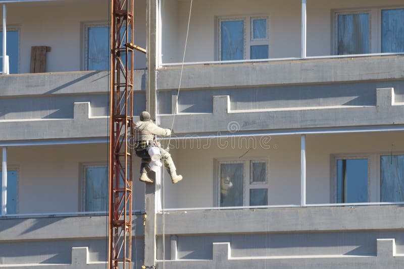 Lavoratore che appende sulle corde alla verniciatura del buildingdin alto fotografia stock libera da diritti Lavoratore che appende sulle corde alla verniciatura del buildingdin alto fotografia stock libera da diritti