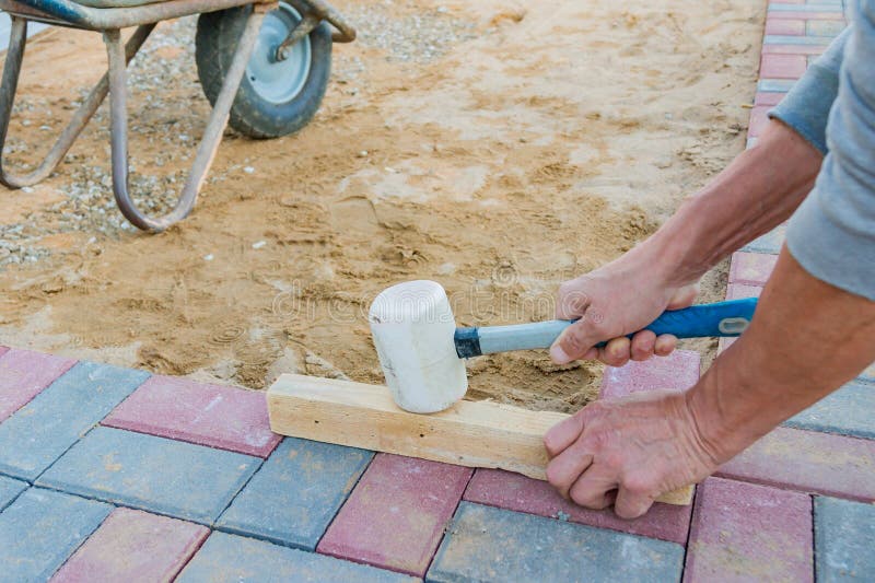 Lavoratore che pone i blocchi di pavimentazione di calcestruzzo rossi e grigi Strada che pavimenta, costruzione immagini stock libere da diritti Lavoratore che pone i blocchi di pavimentazione di calcestruzzo rossi e grigi Strada che pavimenta, costruzione immagini stock libere da diritti