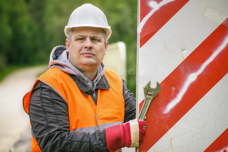 Lavoratore con la chiave inglese sul ponte che ripara il segnale stradale fotografia stock libera da diritti Lavoratore con la chiave inglese sul ponte che ripara il segnale stradale fotografia stock libera da diritti