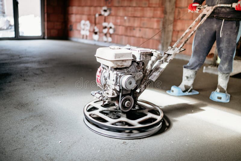 Lavoratore con lo strumento della cazzuola di potere che finisce pavimento di calcestruzzo, tirata, superficie di calcestruzzo re fotografia stock Lavoratore con lo strumento della cazzuola di potere che finisce pavimento di calcestruzzo, tirata, superficie di calcestruzzo re fotografia stock