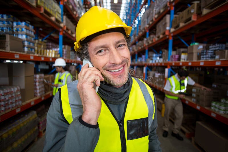 Lavoratore del magazzino che parla sul telefono cellulare fotografie stock Lavoratore del magazzino che parla sul telefono cellulare fotografie stock