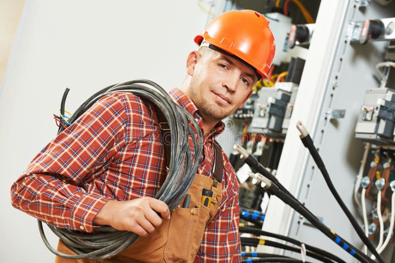 Electrician engineer worker with cable in front of fuseboard equipment. Electrician engineer worker with cable in front of fuseboard equipment