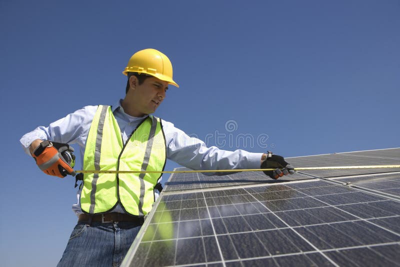 Lavoratore di manutenzione che misura le pile solari fotografie stock Lavoratore di manutenzione che misura le pile solari fotografie stock