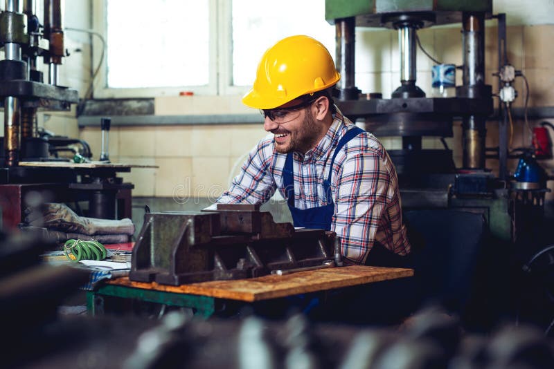 Lavoratore di metallurgia che lavora felicemente nella sua officina con il casco di sicurezza sopra fotografia stock libera da diritti Lavoratore di metallurgia che lavora felicemente nella sua officina con il casco di sicurezza sopra fotografia stock libera da diritti
