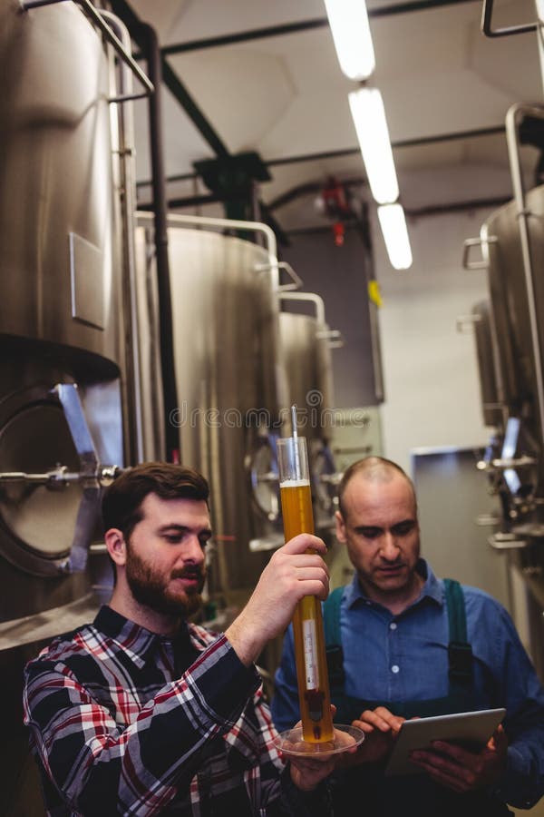 Lavoratore e proprietario che ispezionano birra alla fabbrica di birra fotografia stock libera da diritti Lavoratore e proprietario che ispezionano birra alla fabbrica di birra fotografia stock libera da diritti