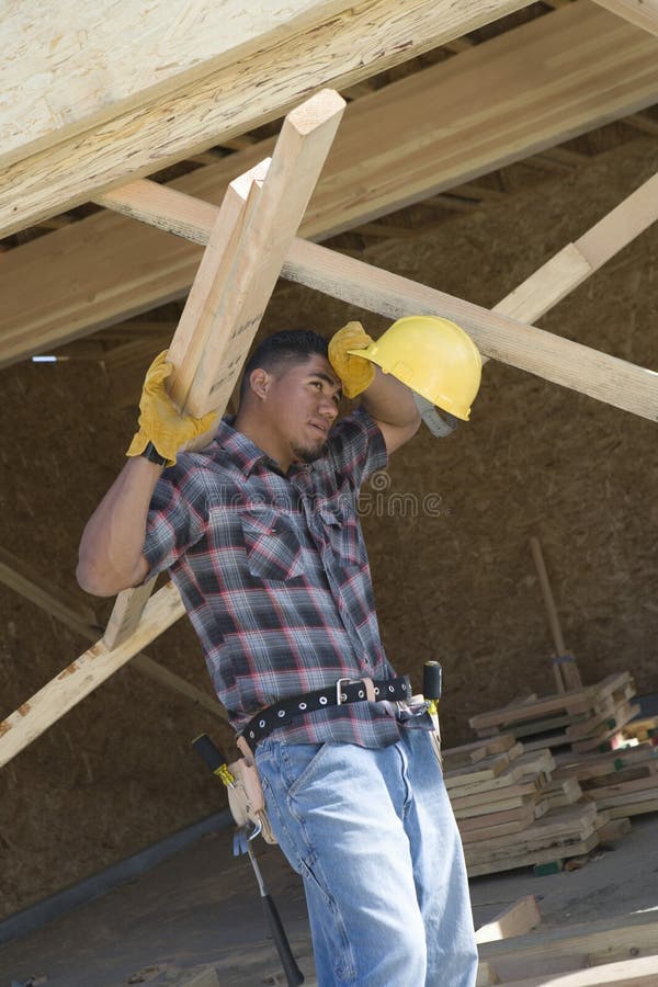 Exhausted worker looking away while holding wooden beams. Exhausted worker looking away while holding wooden beams