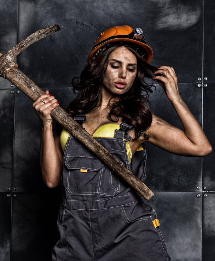 Lavoratore femminile sexy del minatore con il piccone, in tute sopra il suo corpo nudo