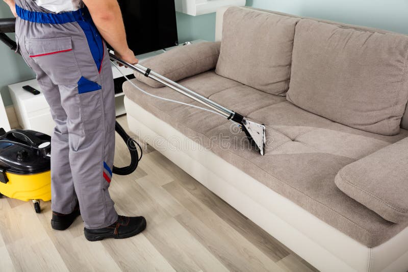 Lavoratore maschio che pulisce Sofa With Vacuum Cleaner fotografia stock Lavoratore maschio che pulisce Sofa With Vacuum Cleaner fotografia stock