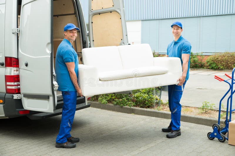 Lavoratori che mettono mobilia e le scatole in camion