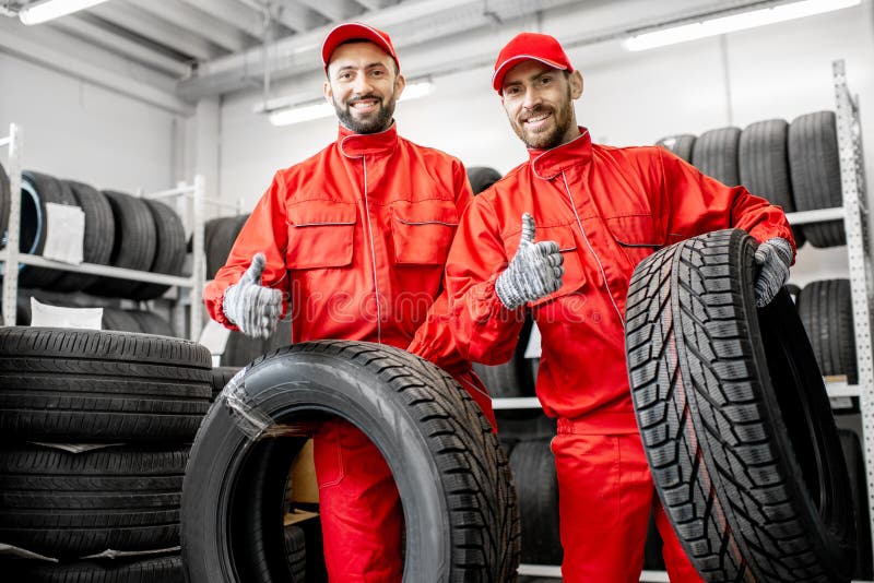 Lavoratori con le gomme di automobile al magazzino fotografia stock libera da diritti Lavoratori con le gomme di automobile al magazzino fotografia stock libera da diritti