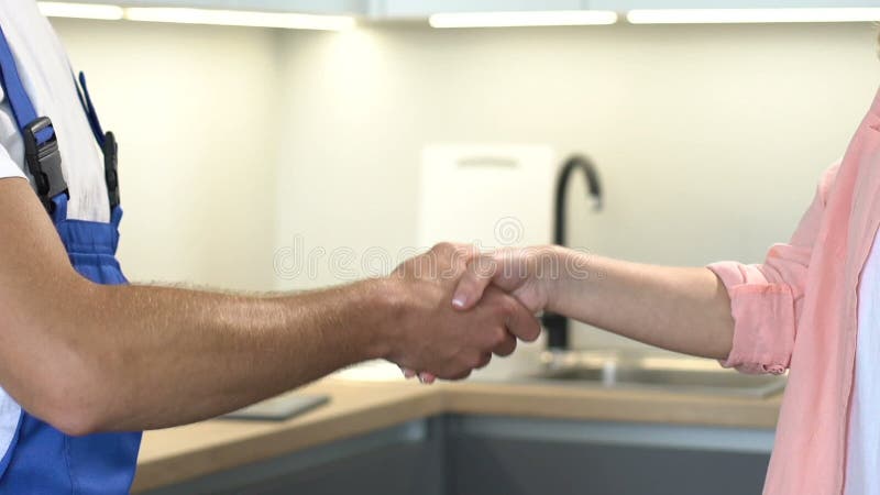 Lavoratrice e cliente maschio stringono la mano dopo aver terminato la riparazione, servizio di qualità