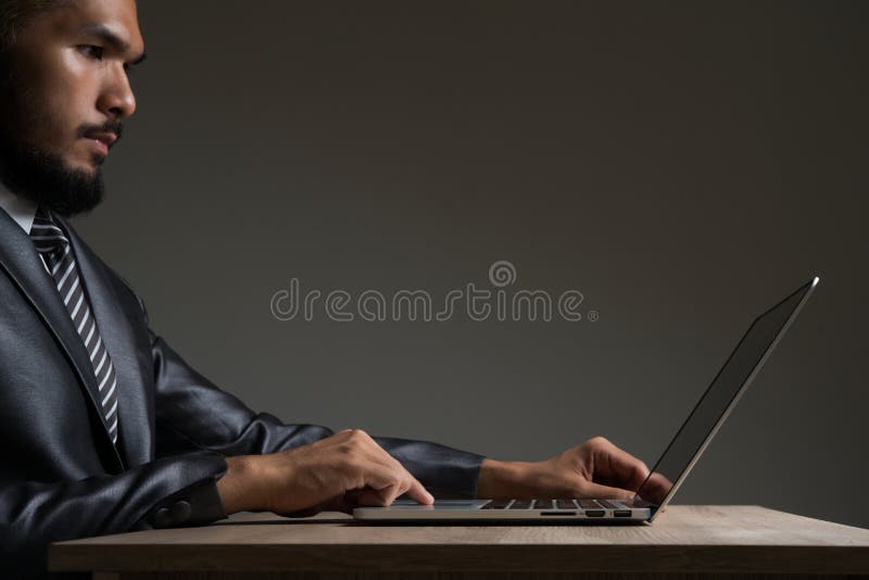 Lavoro di seduta del giovane uomo d'affari con il computer portatile isolato sul nero fotografie stock libere da diritti Lavoro di seduta del giovane uomo d'affari con il computer portatile isolato sul nero fotografie stock libere da diritti