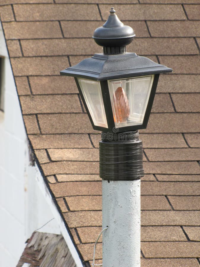 Lawn lamp post. Lawn lamp-post beckons against the pitch of the shingled roof stock photo Lawn lamp post. Lawn lamp-post beckons against the pitch of the shingled roof stock photo