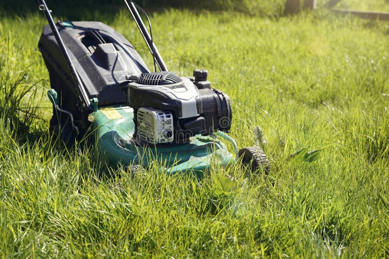 Lawn mower mowing the long grass. Mowing or cutting the very long grass with a green lawn mower in the summer sun stock photos Lawn mower mowing the long grass. Mowing or cutting the very long grass with a green lawn mower in the summer sun stock photos