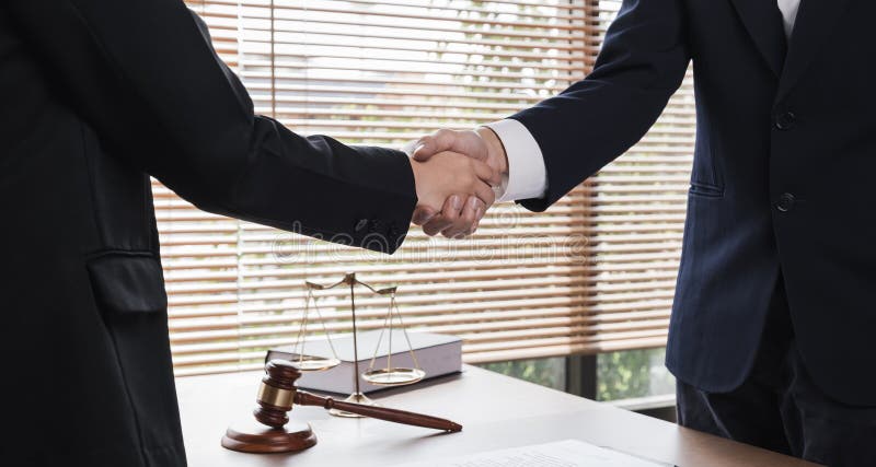 A lawyer and a businesswoman shake hands and reach an agreement on a cooperation contract document. In the lawyer& x27;s royalty free stock image
