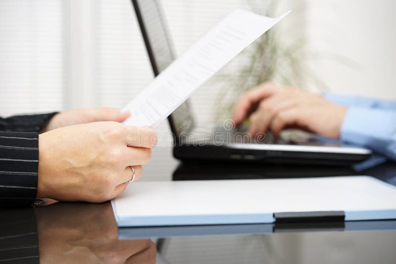 Lawyer is reading contract and bussiness client is typing on lap