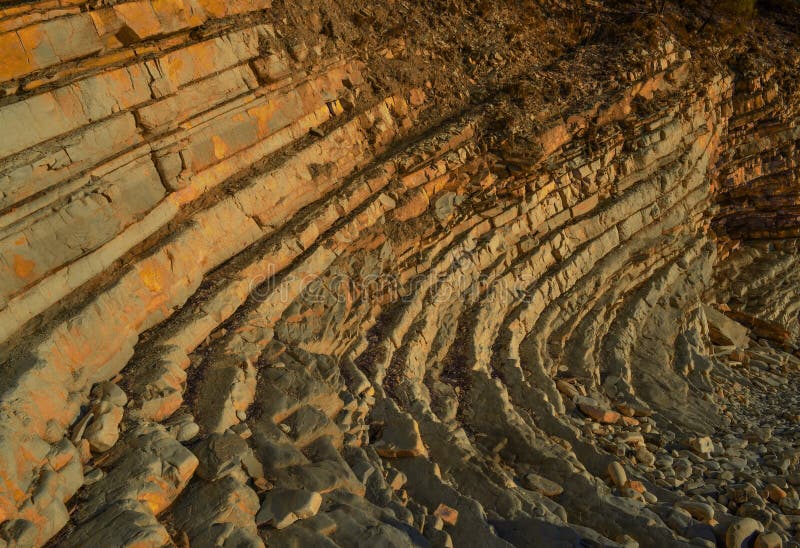 Layered sandy red orange light twisted cliffs made of stone bricks on Black Sea coast, in Blue Bay Golubaya Bay, near Gelenzhik.