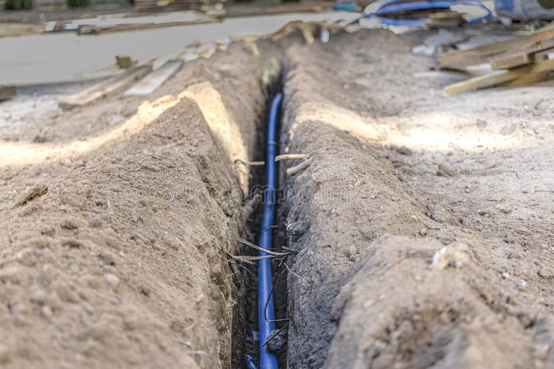 Laying a Blue Electrical Cable in a Trench in the Ground. Underground