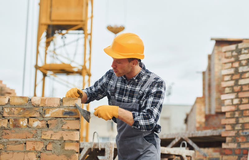 Laying Bricks. Construction Worker in Uniform and Safety Equipment Have