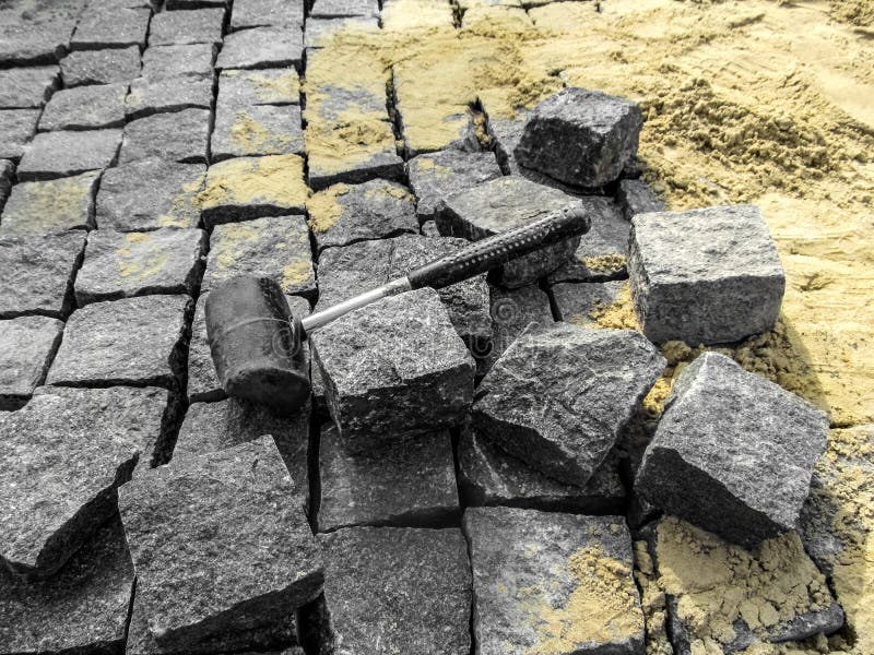 Laying granite paving stones - building background with copy space. A black rubber mallet lies among gray rectangular blocks of stock images