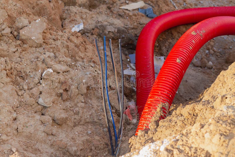 Laying an Insulating Plastic Pipe with an Electric Cable Underground during the Construction of